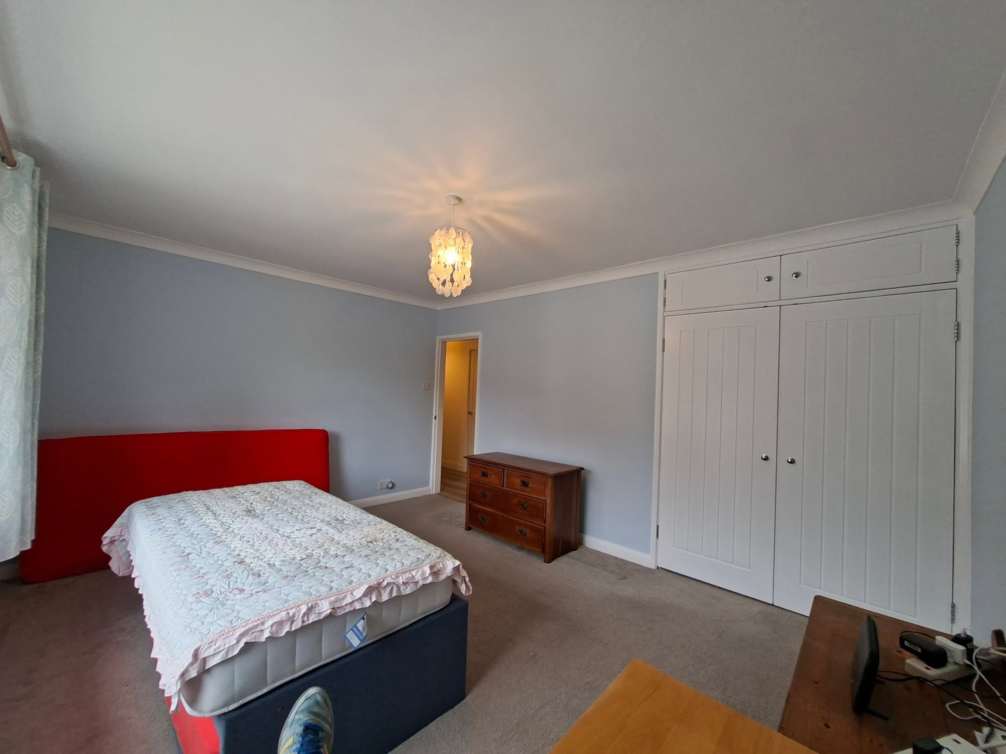 Finished bedroom with pale blue walls and white fitted wardrobes