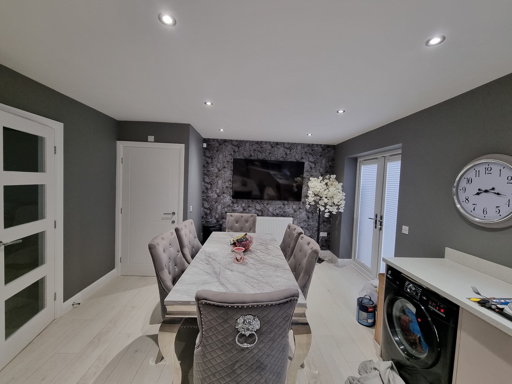 Open plan dining area with grey walls, a dark floral feature wall and white French doors